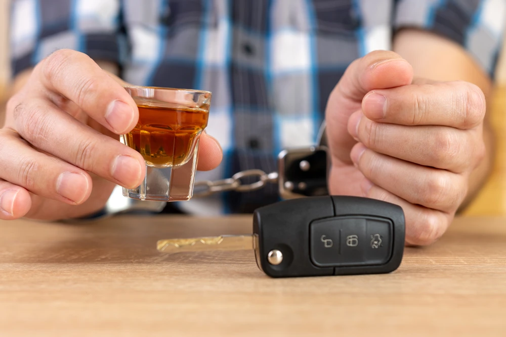 A glass of alcohol and car keys. The concept of driving under the influence of alcohol.
